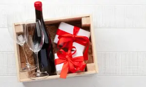 Cadeau gourmand : une bouteille de vin rouge, deux verres et des présents emballés, prêts à être dégustés dans un domaine de Bourgogne.