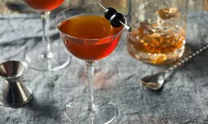 Cocktail au whisky garni de cerises, servi avec un verre de whisky et un jigger. Le whisky est-il bon pour les artères ? Une question à méditer.