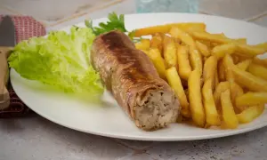 Une belle andouillette grillée avec des frites croustillantes et une feuille de laitue fraîche. Un plat simple et savoureux.