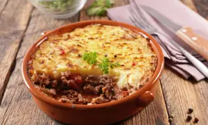 Un plat de hachis parmentier, un classique du repas français, servi dans un plat en terre cuite sur une table en bois.