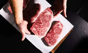 Des mains présentent des steaks de bœuf persillés, marbrés de gras, promettant le meilleur bœuf du monde.