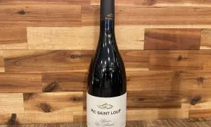 Bouteille de vin rouge du domaine Pic Saint Loup, "Réserve Les Almadies", sur fond de bois.