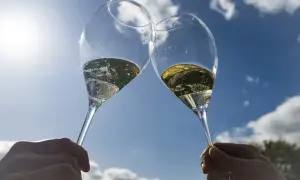 Deux flûtes de champagne pétillant levées en l'air, sous un ciel bleu éclatant. Un toast à Épernay !