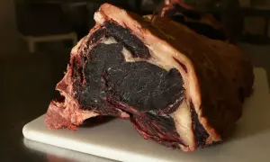 Gros morceau de viande maturée, prêt pour la cuisson. Sa couleur foncée et sa texture fibreuse promettent une saveur intense.