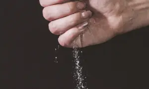 Une main saupoudre du sel, une expression culinaire qui sublime les saveurs.