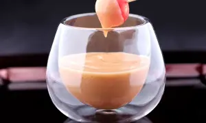 Une tomate cerise trempée dans une sauce cocktail onctueuse, servie dans un verre élégant.