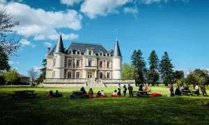 Visite d'un magnifique château dans le Médoc, avec des gens profitant du soleil sur la pelouse.