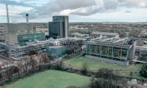 Vue aérienne de la distillerie Midleton, avec ses bâtiments industriels, ses cuves en cuivre visibles à travers une façade vitrée, et un paysage verdoyant en arrière-plan.