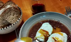 Œufs meurette, un plat d'origine française, servis avec du pain et du vin rouge.