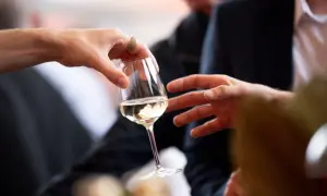 Des mains échangent un verre de vin blanc lors d'une dégustation à Angers.