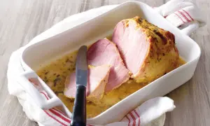 Palette à la diable, tranchée et servie dans un plat blanc avec une sauce dorée. Un couteau est posé sur la viande.