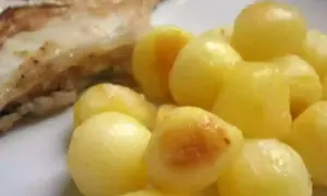 Une assiette de poisson grillé avec une généreuse portion de pomme de terre parisienne, dorée et appétissante.