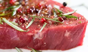 Un morceau de viande rouge, assaisonné de poivre rose, de romarin et d'épices, prêt à devenir l'une des 10 meilleurs viandes du monde.