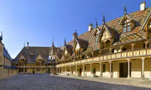 Cour intérieure des Hospices de Beaune, un joyau architectural à visiter. Toits colorés, arcades et pavés de pierre.