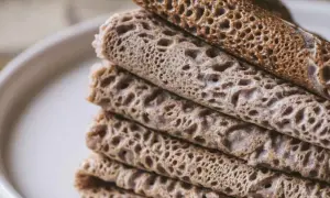 Pile de crêpes et de galettes, certaines roulées, d'autres pliées, avec une texture alvéolée. Un délice qui rappelle le goût de l'andouille.