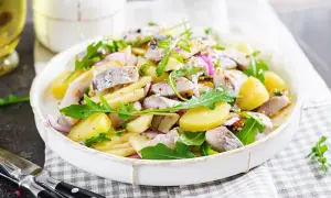 Salade de pommes de terre et hareng à l'huile, garnie de roquette et d'oignons rouges. Une recette simple et savoureuse.