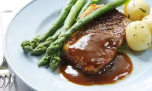 Un délicieux steak servi avec une sauce onctueuse, des asperges croquantes et des pommes de terre nouvelles. Un plat parfait pour un dîner savoureux.