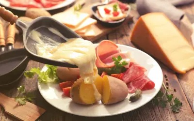 Raclette, le meilleur plat français, avec pommes de terre, charcuterie et fromage fondu. Un délice réconfortant.