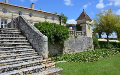 Escalier de pierre menant à un château, avec un étang de nénuphars. Une belle journée pour une visite château Pomerol.
