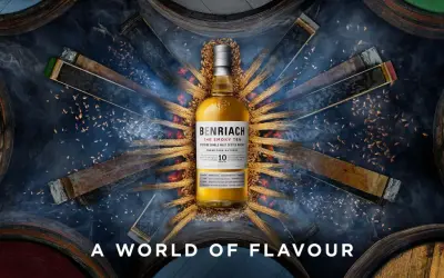 Bouteille de whisky BenRiach The Smoky Ten, entourée de fûts et d'épis de blé, évoquant le savoir-faire de la distillerie.