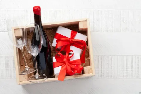 Cadeau gourmand : une bouteille de vin rouge, deux verres et des présents emballés, prêts à être dégustés dans un domaine de Bourgogne.