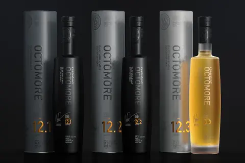 Trois bouteilles d'Octomore, whisky tourbé d'Islay, avec leurs tubes. L'une est dorée, les deux autres noires. Les étiquettes affichent des niveaux de PPM élevés, comme 130.8 PPM.