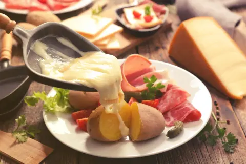 Raclette, le meilleur plat français, avec pommes de terre, charcuterie et fromage fondu. Un délice réconfortant.
