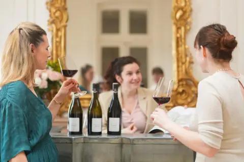 Trois femmes profitent d'une dégustation de vin au Château de Pommard, admirant le contenu de leurs verres.