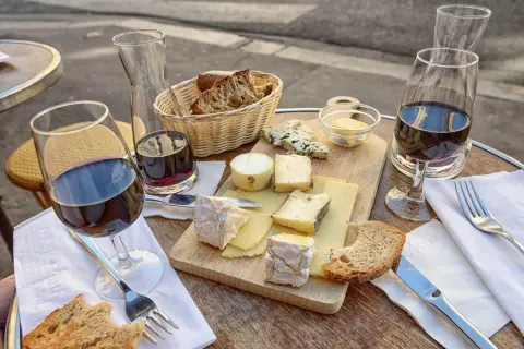 Un plateau de fromages variés, du pain et du vin rouge, une scène qui raconte une belle histoire de la cuisine française.