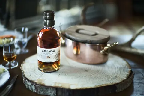 Bouteille d'Aberlour 18 ans, un whisky d'exception, posée sur une tranche de bois. Une expérience de dégustation unique, fruit d'une **création whisky** raffinée.