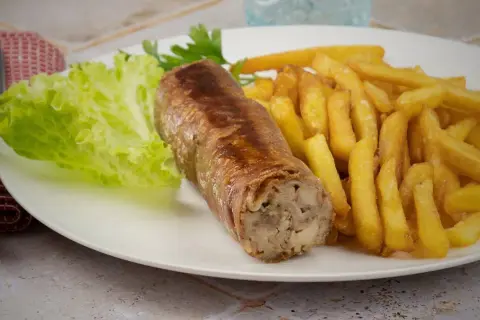 Une belle andouillette grillée avec des frites croustillantes et une feuille de laitue fraîche. Un plat simple et savoureux.