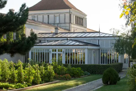 Jardin luxuriant devant une serre élégante, rappelant la beauté du caudalie vignoble.