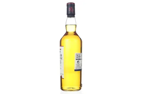 Bouteille de whisky Talisker Dark Storm, ambré, avec étiquette blanche et rouge. Le bouchon est bleu marine avec un lion rouge.