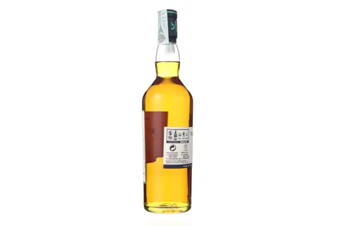 Bouteille de whisky ambré de la distillerie Talisker, avec son étiquette détaillée et son bouchon orné.