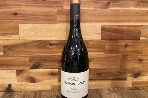 Bouteille de vin rouge du domaine Pic Saint Loup, "Réserve Les Almadies", sur fond de bois.