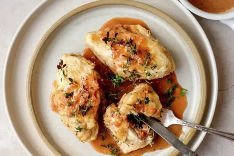 Trois morceaux de poulet généreusement nappés d'une sauce onctueuse, garnie de thym frais. Un plat qui évoque la richesse de la gastronomie lyonnaise.