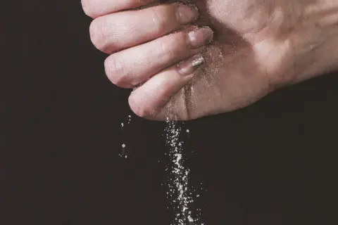 Une main saupoudre du sel, une expression culinaire qui sublime les saveurs.