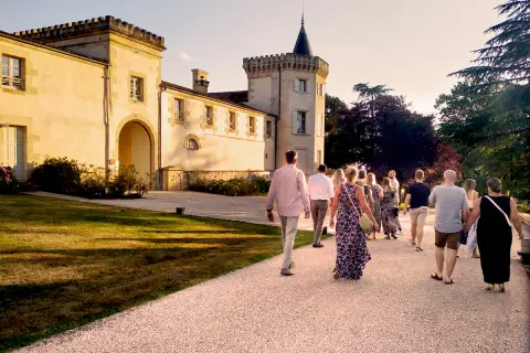 Un groupe de personnes se promène sur le chemin menant au **château Toulouse Lautrec** au coucher du soleil.