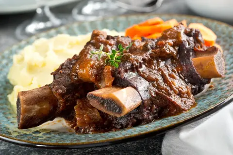 Plat de côte au four, tendre et savoureux, servi avec purée et carottes. Le temps de cuisson est parfait pour cette viande.