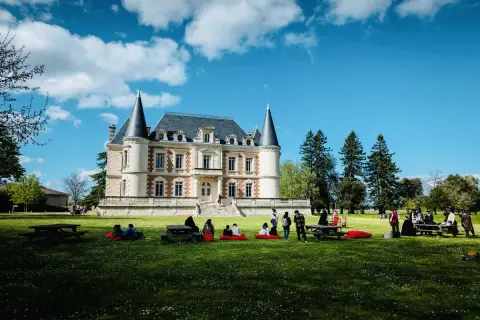 Visite d'un magnifique château dans le Médoc, avec des gens profitant du soleil sur la pelouse.