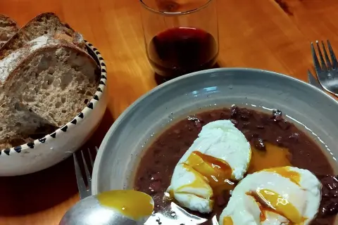 Œufs meurette, un plat d'origine française, servis avec du pain et du vin rouge.
