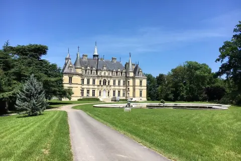 Château majestueux sous un ciel bleu, avec une allée menant à l'entrée. Un lieu idéal pour déguster un champagne Le Gallais.