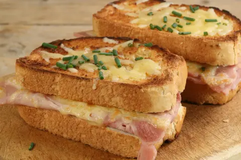 Deux croque monsieur bistrot, dorés et gratinés, garnis de jambon et fromage fondant, parsemés de ciboulette fraîche.