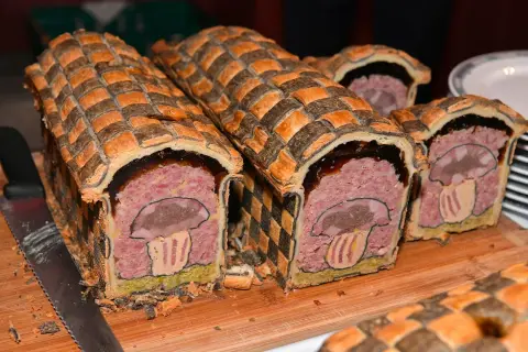 Pâté en croûte d'origine, décoré d'un champignon stylisé. Une œuvre culinaire qui raconte l'histoire de ce plat traditionnel.