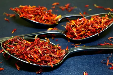 Trois cuillères remplies de filaments rouge orangé, une épice précieuse.