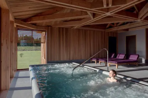 Détente dans un chateau spa à Bordeaux. Une femme profite d'un jacuzzi avec vue sur les vignes.