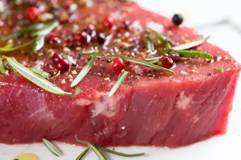 Un morceau de viande rouge, assaisonné de poivre rose, de romarin et d'épices, prêt à devenir l'une des 10 meilleurs viandes du monde.