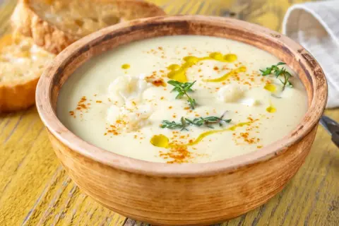 Un onctueux potage Dubarry, garni de chou-fleur, d'huile d'olive et de thym, servi avec des toasts grillés.