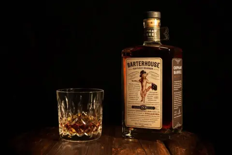 Verre de bourbon ambré et bouteille Orphan Barrel Barterhouse 20 ans. Une dégustation pour apprécier la différence whiskey bourbon.