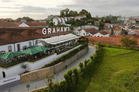 Le vignoble Porto District, avec le nom "GRAHAM'S" en lettres blanches sur le toit, offre une vue sur des bâtiments traditionnels et des champs verdoyants.
